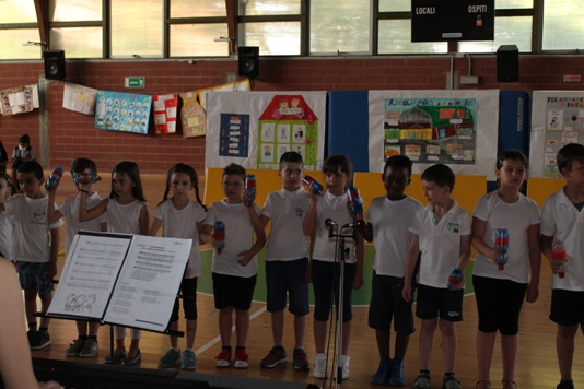 Gli alunni cantano ritmando con strumenti di recupero.